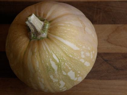 A ripe Seminole pumpkin placed on a wood surface, as viewed above and slightly skew